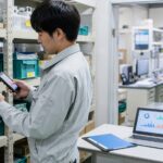 部品棚でスマホを使い在庫を確認する製造業の作業者